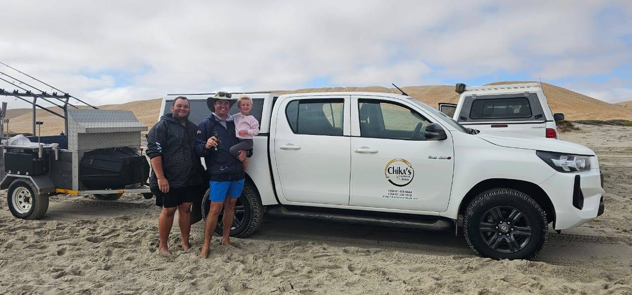 Happy customers with a Chika's Toyota Hilux on the beach